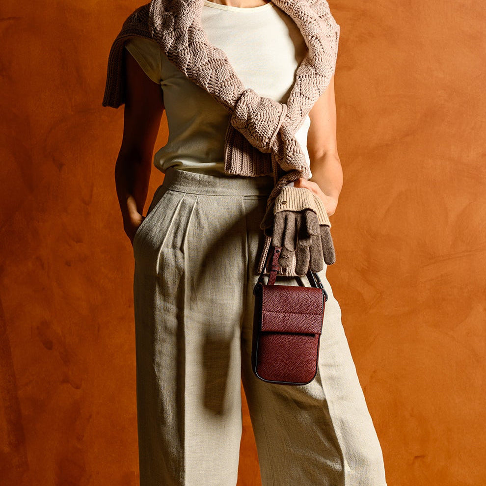 Woman in a stylish outfit with a fur stole, white top, and beige pants against an orange wall.